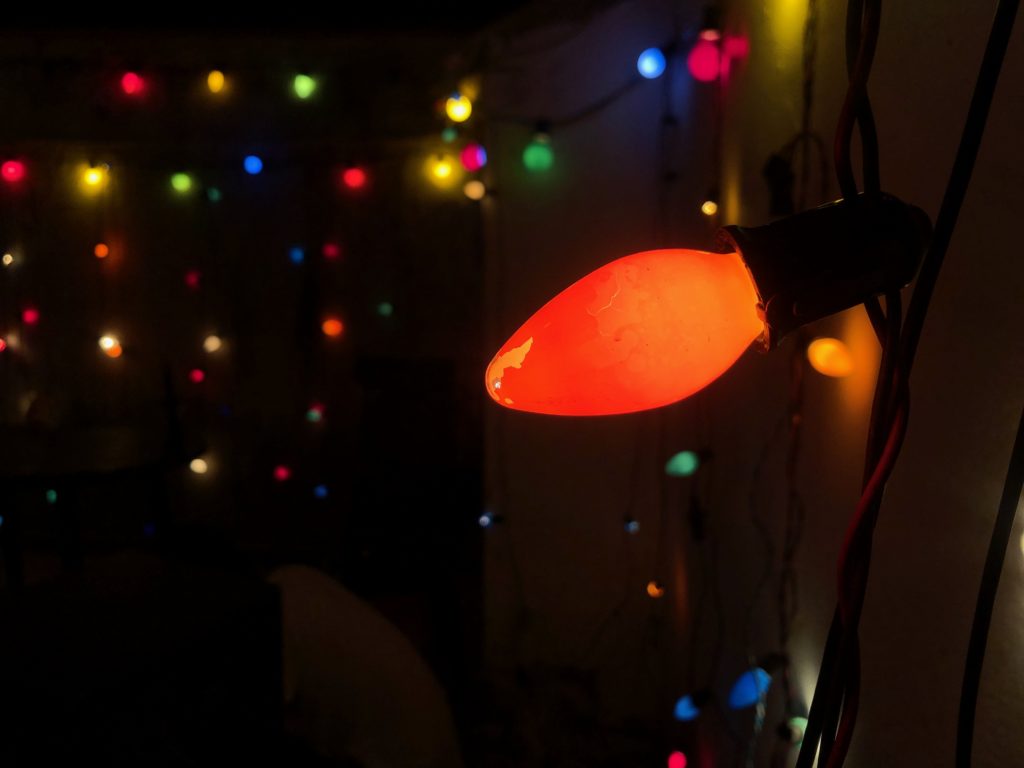 A closeup of an orange bulb, with various out-of-focus multicolour lights in the background.