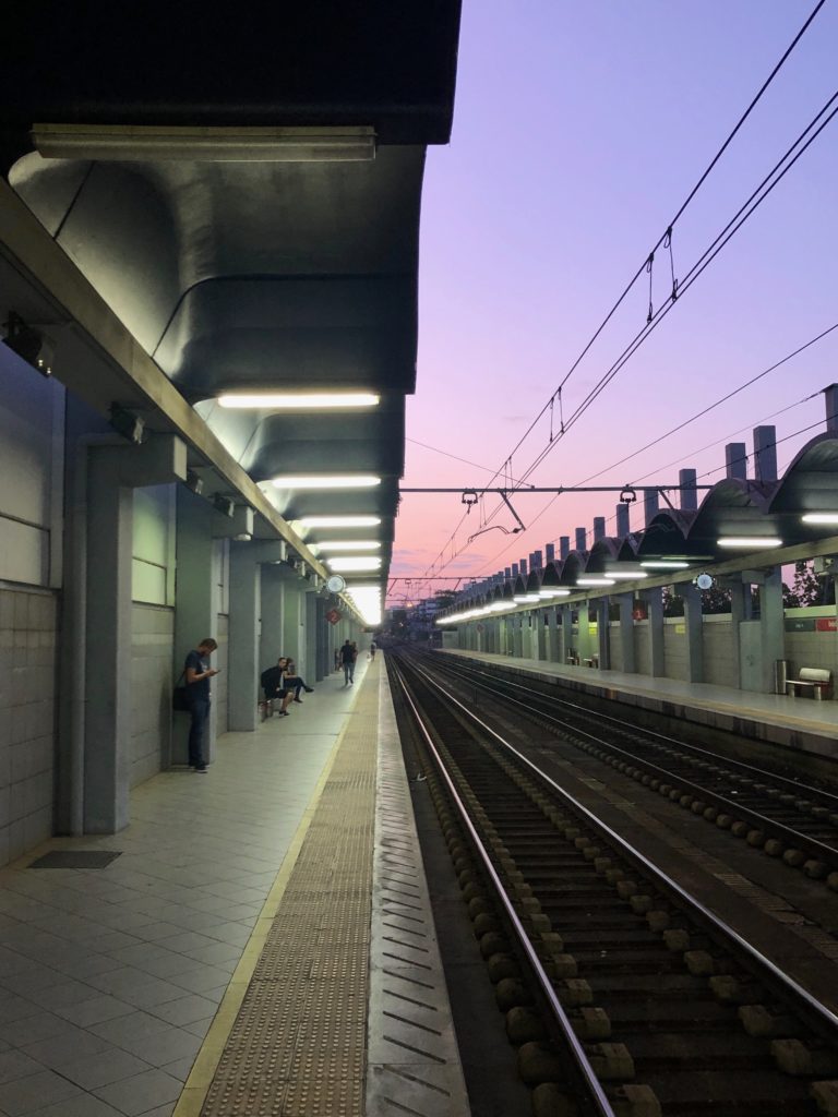 A pink, purple, and orange sunrise over the train lines of a station.
