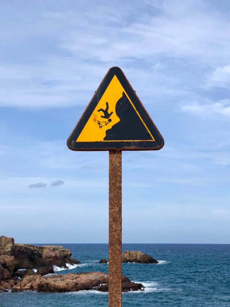 A sign warning of the risk of falling off a cliff.