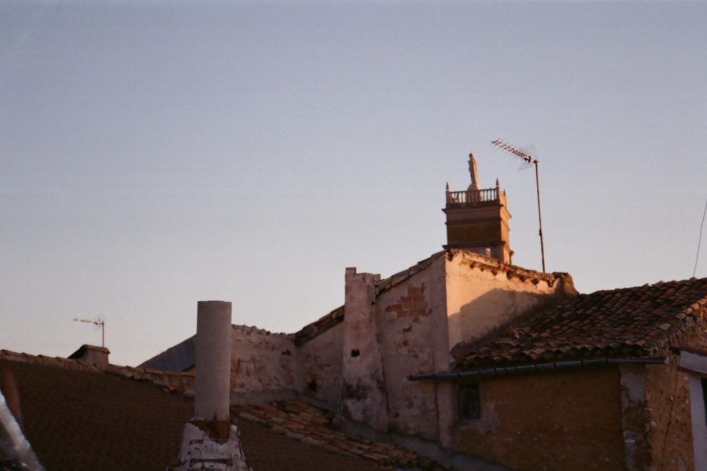 A film photo of sunlight setting on roofs and a church.