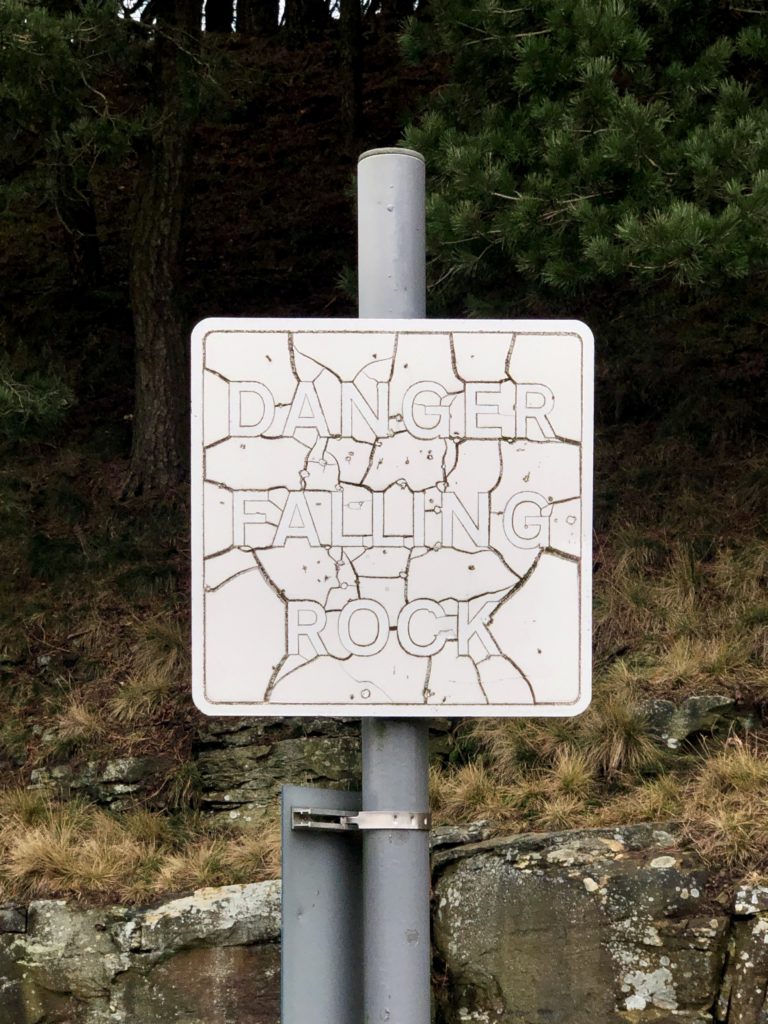 A "Danger: Falling Rock" sign which has bleached and cracked in the sun.