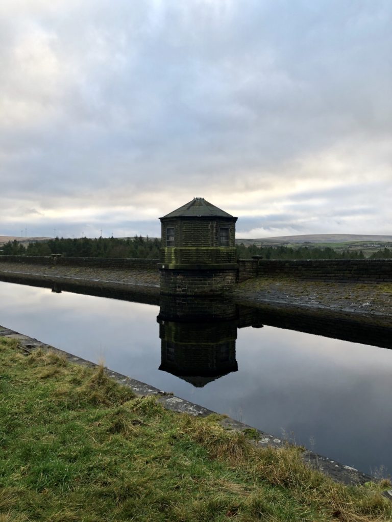 A reservoir building is reflected in the water.