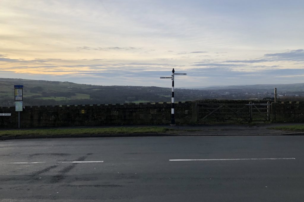 An old street sign against the backdrop of Burnley.