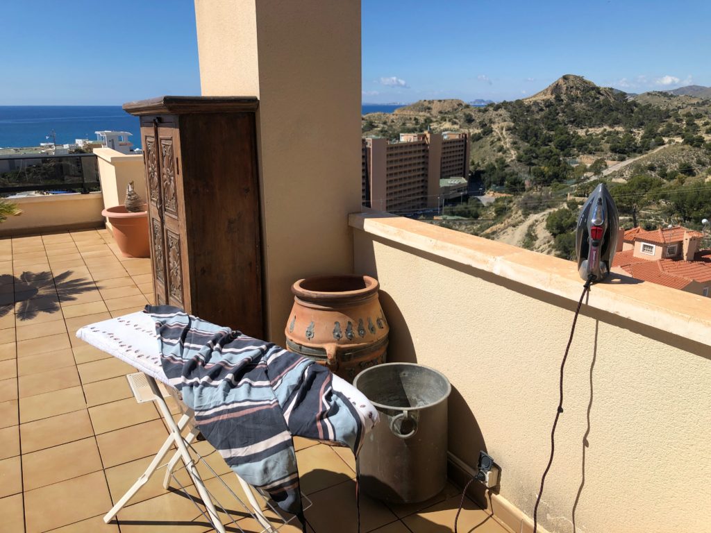 An ironing board set up on a terrace overlooking the sea.