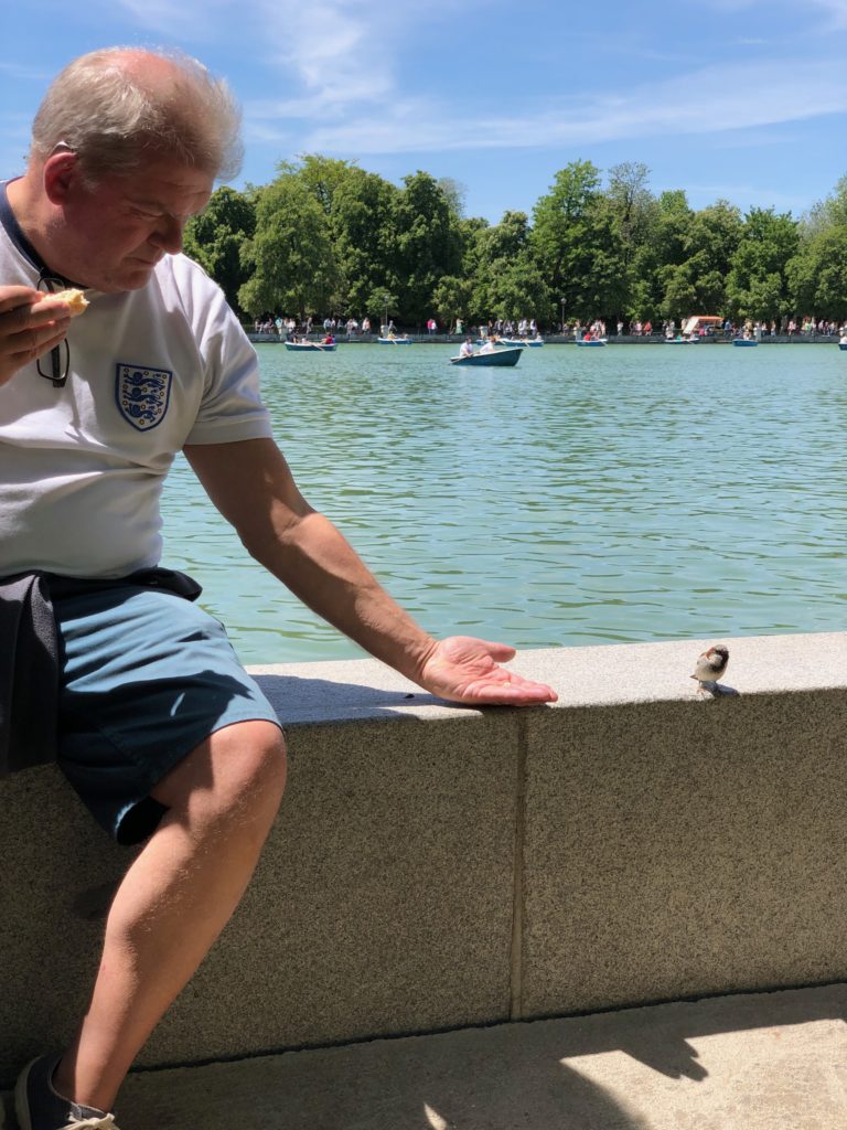 My dad tries to feed a bird by the lake.