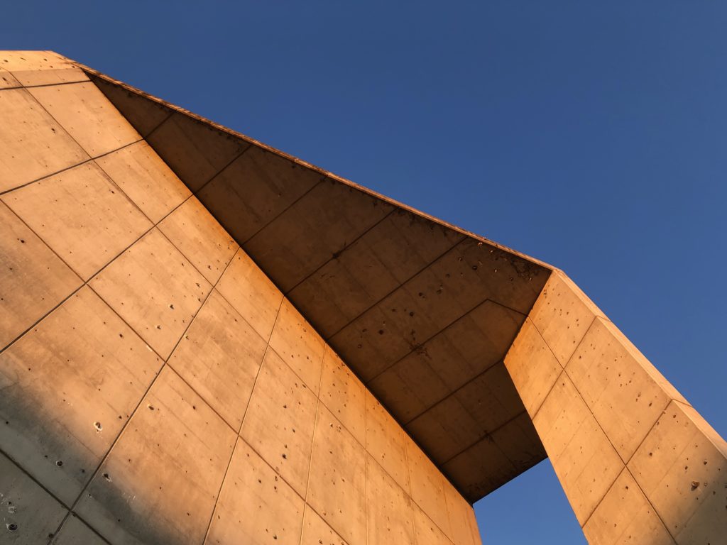 Looking up at the angular forms of a concrete structure in Parque de las Delicias, Madrid, Spain.