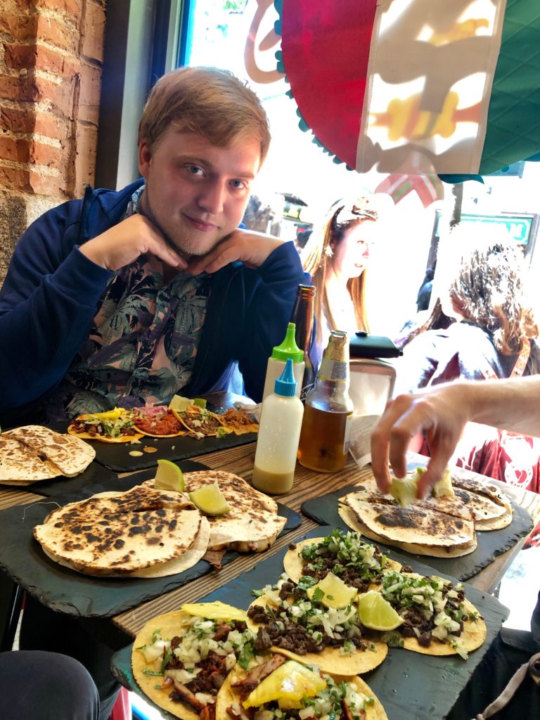 A photo of me sat behind a table full of tacos.