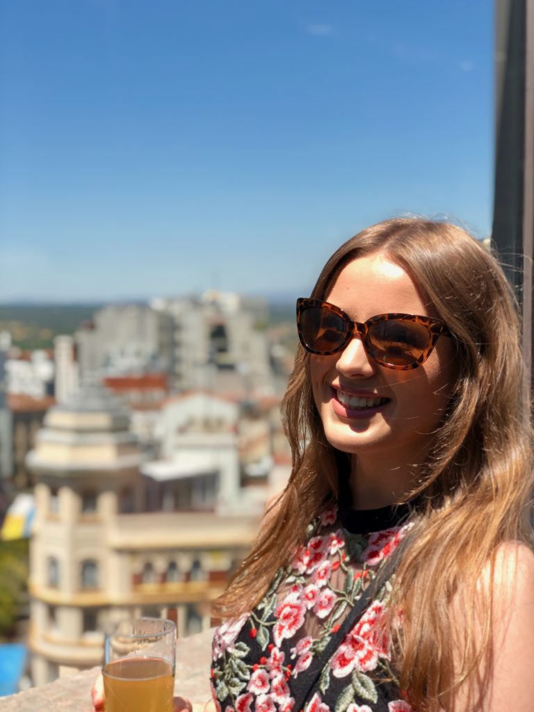 Ellie stands on the terrace of El Corte Inglés, the buildings of Gran Vía in the background.
