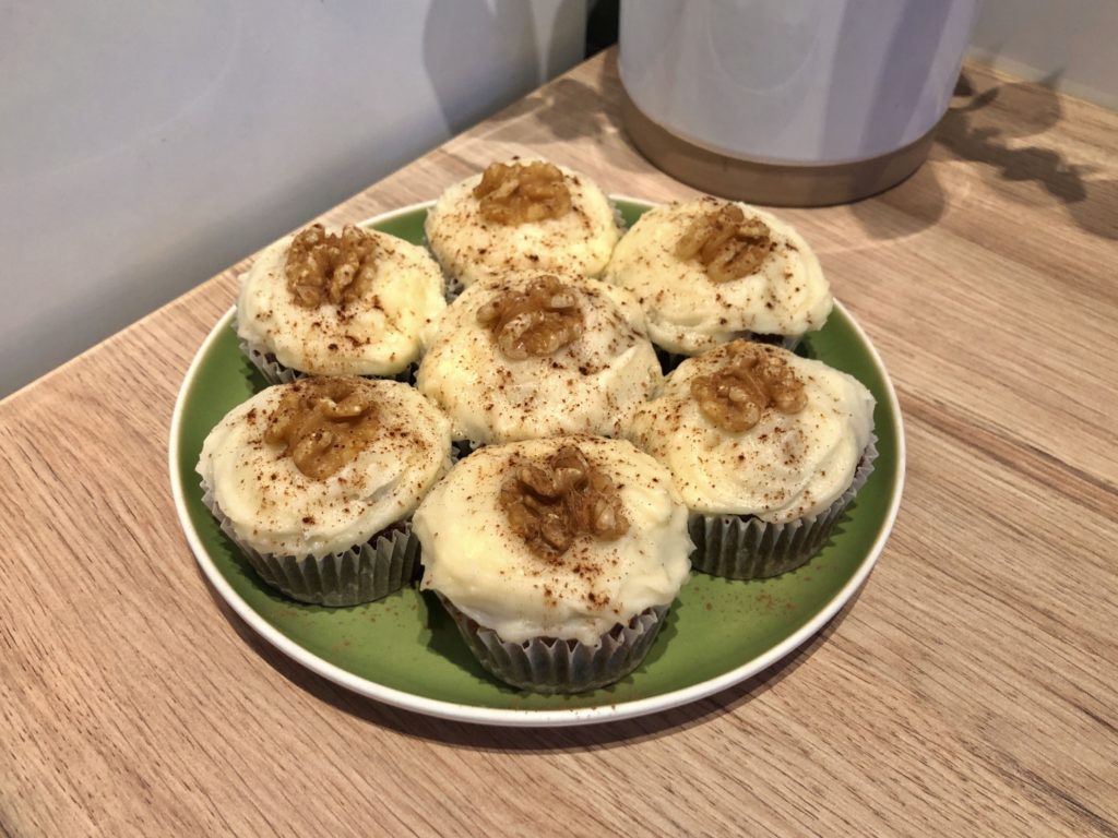 A plate full of seven carrot cake buns topped with walnuts and cinnamon.